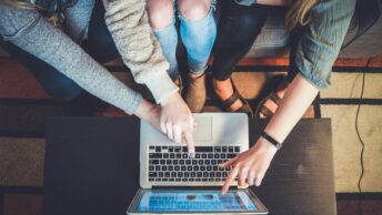 three person pointing the silver laptop computer